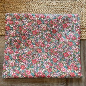 Pode incluir: Um tecido retangular com um padr&atilde;o floral denso. O design apresenta pequenas flores vibrantes em tons de rosa, vermelho e branco, sobre um fundo verde e azul. O tecido &eacute; provavelmente algod&atilde;o ou um material semelhante.