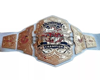 May include: A gold and white wrestling championship belt. The belt features gold plates with the text "Knockouts World" and "TNA Champion" in blue. The belt is made of white leather.