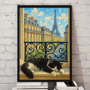 May include: A framed art print depicts a black and white cat sleeping on a windowsill overlooking a Parisian street scene. The Eiffel Tower is visible in the background, with ornate wrought iron railings in the foreground.