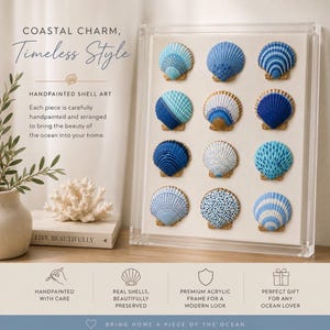 Op de afbeelding: Een heldere acryl lijst met twaalf handbeschilderde schelpen in een raster. De schelpen hebben diverse blauw-witte patronen, waaronder strepen, stippen en effen tinten. De tekst luidt COASTAL CHARM, Timeless Style, HANDPAINTED SHELL ART.