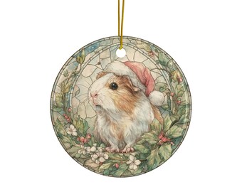 Puede incluir: Adorno navideño redondo con una ilustración en acuarela de un conejillo de indias con un gorro de Papá Noel. El conejillo de indias está rodeado de acebo y flores blancas, sobre un fondo de estilo vidriera. Una cuerda dorada está adjunta.