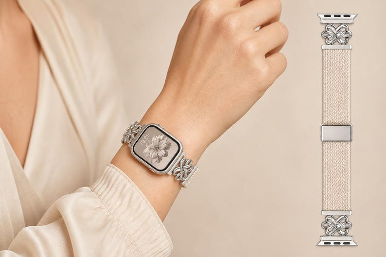 Puede incluir: Una correa para reloj inteligente con una banda beige texturizada y conectores de metal plateado en ambos extremos. Los conectores muestran un dise&ntilde;o intrincado de nudos entrelazados. Una hebilla central de metal plateado asegura la correa.