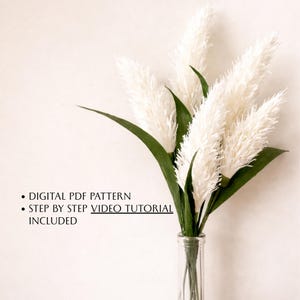 Puede incluir: Un ramo de hierba de la Pampa esponjosa de color crema con hojas verdes largas en un jarrón de vidrio transparente. La imagen incluye el texto: DIGITAL PDF PATTERN, STEP BY STEP VIDEO TUTORIAL INCLUDED.