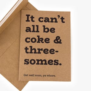 May include: A brown greeting card with the text "It can't all be coke & threesomes." and "Get well soon, ya whore." in black. The card is inside a matching brown envelope, partially open.