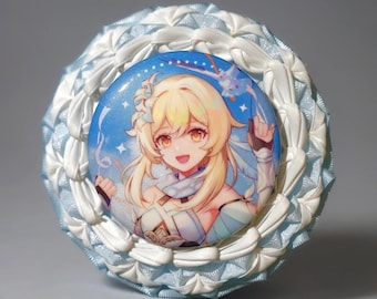 May include: A circular pin-back button featuring an anime-style illustration of a blonde character with orange eyes, set against a blue background with white sparkles. The button is framed by a ruffled border of light blue and white satin ribbon.