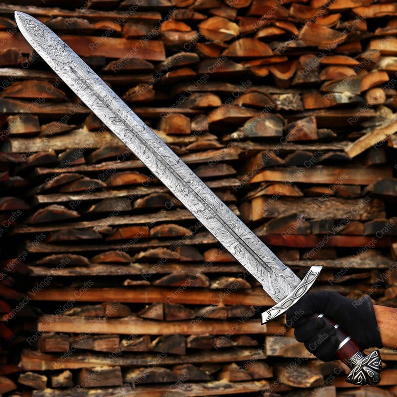 May include: A long, silver sword with an ornate, patterned blade and a detailed hilt. The sword is held against a backdrop of stacked firewood. The blade has a unique design, and the hilt features decorative elements.