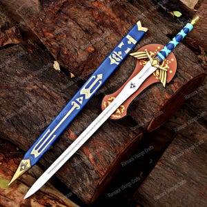 May include: A decorative sword with a silver blade, blue and gold handle, and a matching blue sheath. The sword rests on a wooden stand with a gold emblem. The design is reminiscent of a fantasy video game.