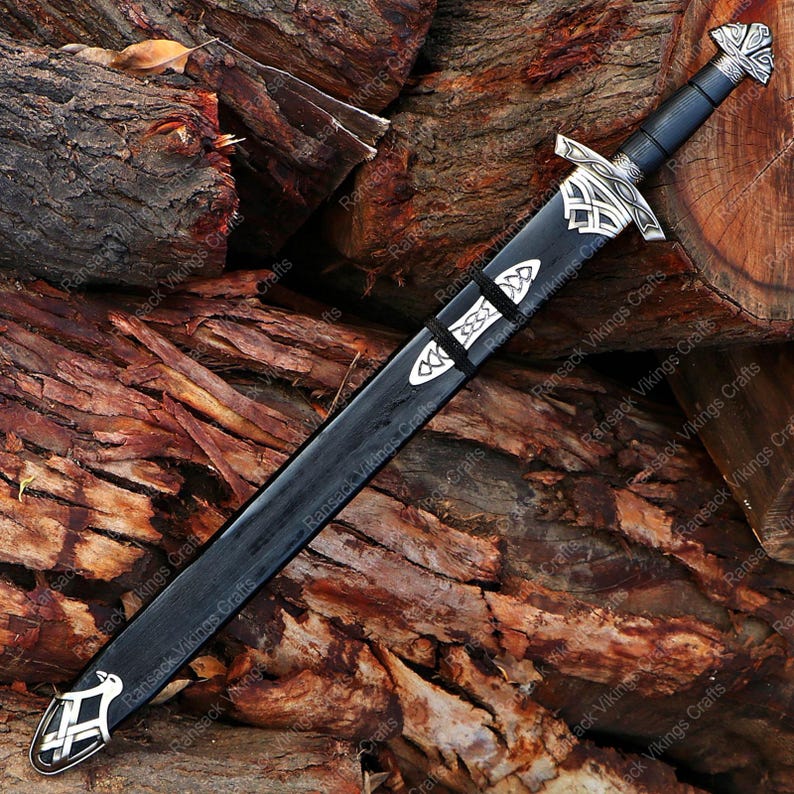 May include: A black sword with a silver hilt and accents, resting on a pile of wood. The sword features intricate designs on the hilt and scabbard, with a black handle and a silver crossguard. The scabbard is black with silver details.