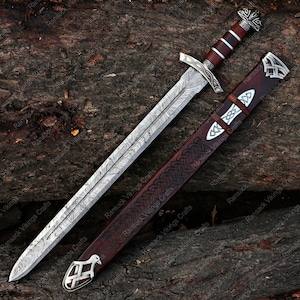 May include: A detailed image of a Viking sword with a patterned blade and a wooden handle. The sword is displayed with its matching leather sheath, featuring intricate designs and silver accents. The overall color scheme is brown, silver, and dark red.