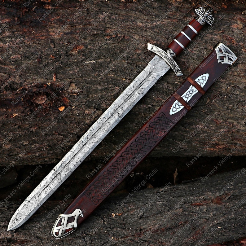 May include: A detailed image of a Viking sword with a patterned blade and a wooden handle. The sword is displayed with its matching leather sheath, featuring intricate designs and silver accents. The overall color scheme is brown, silver, and dark red.