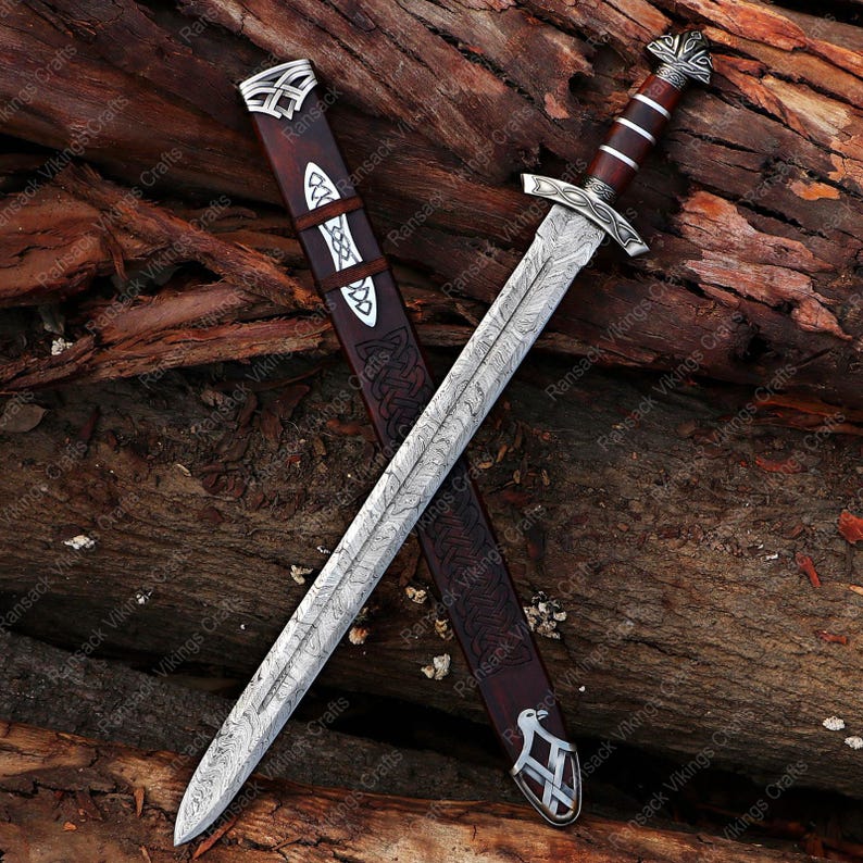 May include: A detailed image of a Viking sword with a patterned blade and a wooden handle. The sword is displayed with its leather sheath, featuring intricate designs. The handle is a dark brown color, and the blade has a silver finish.