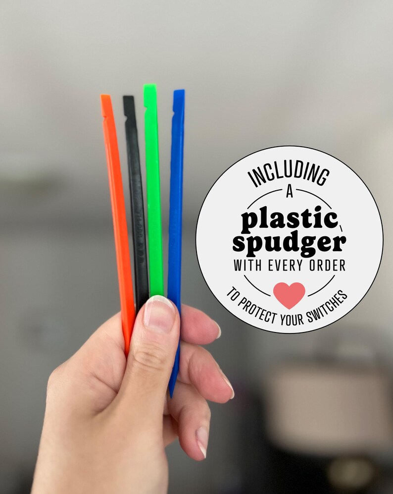 May include: Four thin plastic spudger tools in orange, black, green, and blue. A circular white sticker features the black text: INCLUDING A plastic spudger WITH EVERY ORDER TO PROTECT YOUR SWITCHES, with a small red heart icon below the text.