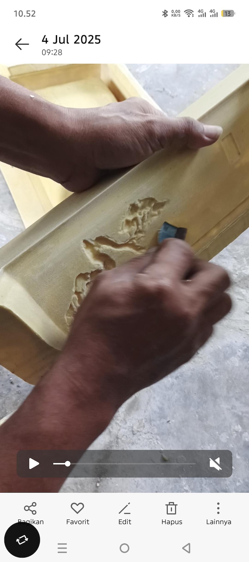 May include: A person is sanding a light brown wooden object with a carved design. The object appears to be a tray or a similar item. The image is taken from a close-up angle, showing the details of the wood and the sanding process.