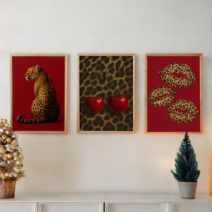 May include: Three framed art prints. The first shows a leopard on a red background. The second has two red cherries against a leopard print background. The third shows leopard print lips on a red background.