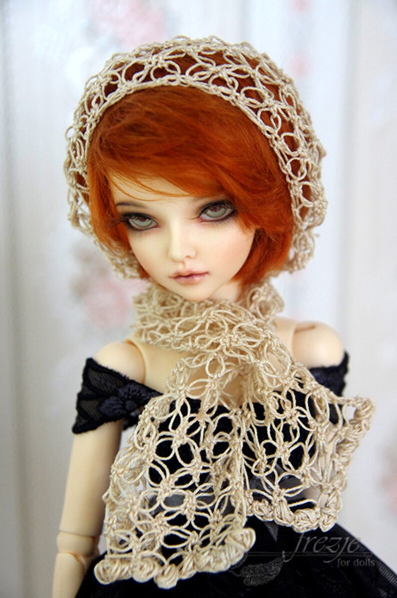 K&ouml;nnte beinhalten: Eine Puppe mit roten Haaren, die einen geh&auml;kelten Hut und Schal tr&auml;gt. Hut und Schal sind cremefarben und haben ein Blumenmuster. Die Puppe tr&auml;gt ein schwarzes Kleid.