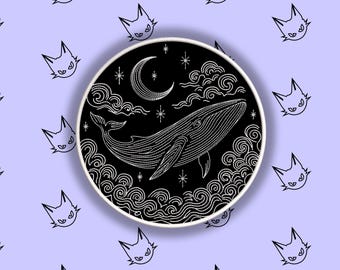 Könnte beinhalten: Ein schwarz-weißer, gestickter Aufnäher mit einem Wal unter einem Mond und Sternen. Das Design ist von wirbelnden Wolken und Wellen umgeben. Der Hintergrund ist helllila mit sich wiederholenden Katzenkopf-Illustrationen.
