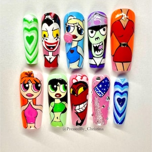 May include: A set of ten long, coffin-shaped acrylic nails, each hand-painted with cartoon character designs. The designs include hearts, villains, and Powerpuff Girls characters in vibrant colors like green, red, blue, and pink. The artist's name is written on the image.