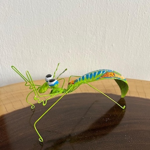 Handmade praying mantis with natural seeds, vibrant colors, its decorative painting design, creating a unique piece