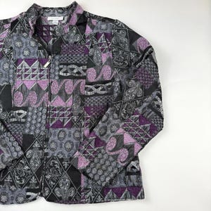 May include: A quilted jacket with a patchwork design in black, gray, and purple. The jacket features a zipper closure and a collar. The pattern includes geometric shapes and floral motifs, creating a unique and stylish look.