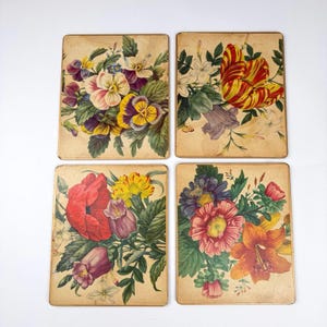May include: A set of four rectangular floral prints, each displaying a different arrangement of flowers. The prints feature a variety of colours, including red, yellow, purple, and orange, set against a beige background. The prints have a vintage appearance.