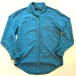 Op de afbeelding: Een turquoise overhemd met knopen en een klein, zich herhalend geometrisch patroon in een lichtere tint. Het shirt met lange mouwen heeft een enkele borstzak en een klassieke kraag. De stof lijkt een lichtgewicht materiaal te zijn.