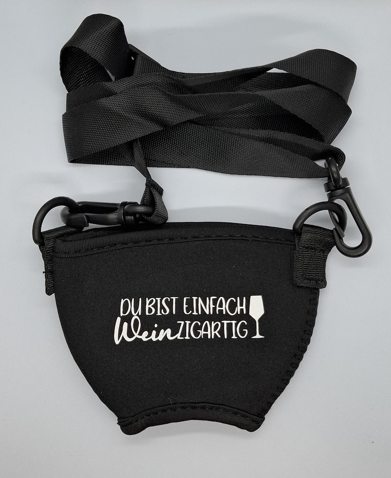 Schwarzer Neopren-Weinflaschenhalter mit einem verstellbaren schwarzen Gurt und Clips. Der Halter hat den weißen Text "DU BIST EINFACH WeinZIGARTIG" und eine Weinglas-Grafik.