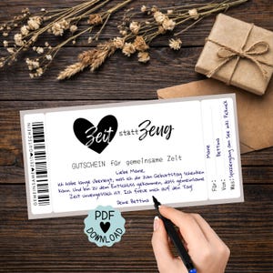 May include: A white gift certificate with the text "Zeit statt Zeug" and "GUTSCHEIN für gemeinsame Zeit" in black. The certificate includes a handwritten message and a PDF download icon. A small gift box and dried flowers are in the background.