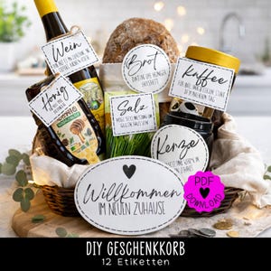 May include: A gift basket containing bread, wine, honey, coffee, and candles, with German labels. The basket sits on a wooden board, with a sign reading "Welcome to your new home." The basket is filled with various items.