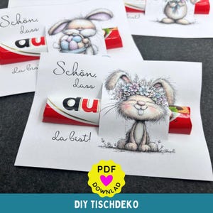 May include: Easter-themed greeting cards with illustrations of bunnies, each holding a Kinder Bueno chocolate bar. The cards feature handwritten text in German, with a yellow PDF download icon and the words "DIY TISCHDEKO".