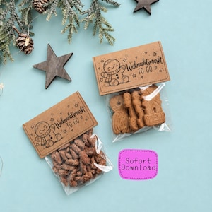 Può includere: Due sacchetti di plastica trasparente con etichette in carta marrone raffiguranti un omino di pan di zenzero e il testo "Weihnachtsmarkt TO GO". Un sacchetto contiene biscotti marroni, l'altro noci. Un riquadro rosa riporta "Sofort Download".