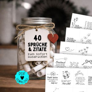Könnte beinhalten: Ein klares Glasgefäß gefüllt mit gerollten weißen Papierstreifen, verziert mit einer Paketschnur und einem kleinen roten Holzherz. Ein weißes Etikett trägt die Aufschrift 40 SPRÜCHE & ZITATE zum sofort ausdrucken. Daneben liegen ausgedruckte Blätter mit schwarzen Strichzeichnungen und deutschem Text.