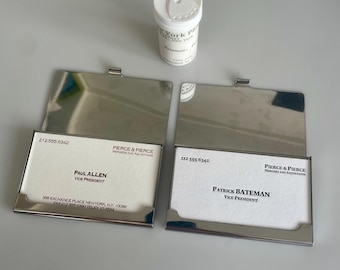 Réplica de American Psycho: Tarjetas de presentación de Patrick Bateman y Paul Allen con soporte y frasco de pastillas. Objeto coleccionable de la película.
