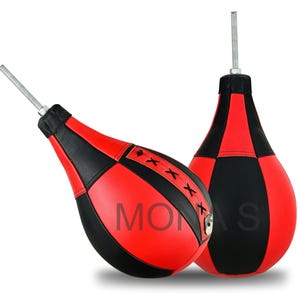 Op de afbeelding: Twee rood-zwarte druppelvormige speedbags met metalen staven die zich van bovenaf uitstrekken. De tassen hebben een gestikt ontwerp en het woord "MONAS" is op één te zien. Voor bokstraining.