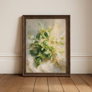 May include: A framed botanical print featuring a detailed painting of basil with green leaves and white flowers. The artwork is set against a soft, light background and framed in a dark brown wooden frame. The painting is displayed on a wooden floor.