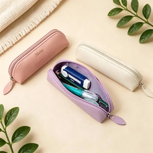 Op de afbeelding: Drie etuis in roze, crème en lavendel. Het roze etui is voorzien van de naam Maddyn in cursief schrift. Het lavendelkleurige etui is geopend en toont een blauwe rolsnijder, een groene pen en andere schrijfwaren. Elk etui heeft een ritssluiting.