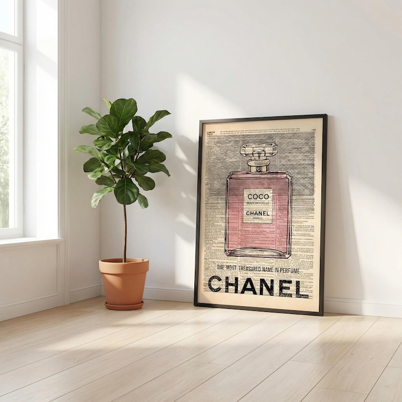 May include: Framed art print featuring a pink perfume bottle design with the text "COCO MADEMOISELLE CHANEL PARIS". The print is set against a vintage newspaper background, with the word "CHANEL" prominently displayed at the bottom.