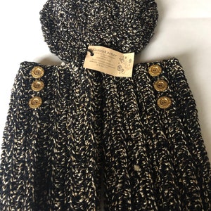 May include: Black and white knitted leg warmers with gold buttons. The leg warmers are paired with a matching black and white knitted beret. The tag reads "SusiesKorner Handmade with love. Each item is individually made.  Bulk wholesale orders welcome.  etsy.com/shop/SusiesKorner  #Etsy #ShopSmall"