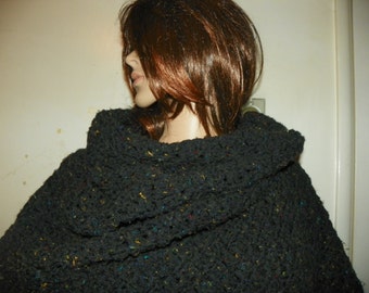 Puede incluir: Poncho de crochet negro con motas de colores. El poncho tiene un cuello grande y doblado.