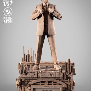 May include: A brown statue of a man in a suit and sunglasses, standing on a detailed base with the word "MATRIX" displayed. The statue is labeled "PRESUPPORTED TESTED SCALE 1/6 RESIN & FDM".