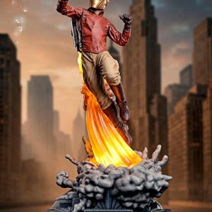 May include: A detailed statue of a figure in a red jacket, tan pants, and a gold helmet, holding a gun and flying with a jetpack. The figure is atop a base with the text "THE ROCKETEER" and a cityscape background.