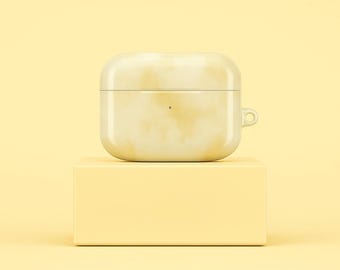 May include: A yellow and white marbled AirPods case rests on a matching yellow rectangular block. The case has a small loop on the side and a small dot on the front. The background is a solid yellow.