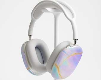 May include: White over-ear headphones with a light gray headband and earcups. The earcups have a colorful, iridescent design with blue, purple, and gold tones. The headphones are displayed on a white stand.