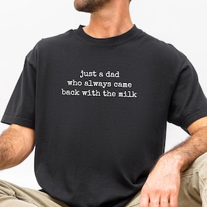 Peut inclure: Un t-shirt noir à manches courtes avec un texte blanc de style machine à écrire sur la poitrine qui indique : just a dad who always came back with the milk. Le t-shirt présente une encolure ronde et une coupe standard en noir uni.