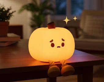 May include: A glowing, cartoon-style pumpkin night light with a sad face and small yellow shoes. The pumpkin is sitting on a wooden table. Two yellow stars are above the pumpkin.