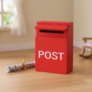 May include: A miniature red mailbox with the word "POST" in white lettering. The mailbox has a small roof and a slot for mail. A rolled-up paper with gold string is next to the mailbox. The scene is set on a wooden surface.