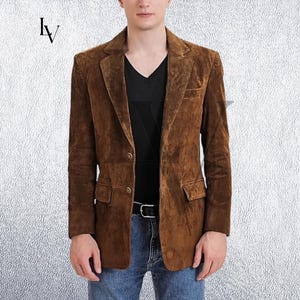 May include: A brown suede blazer with a two-button closure, notched lapels, and two front pockets. The blazer is worn over a black V-neck shirt and blue jeans. The image features the letters "lv" in the upper left corner.