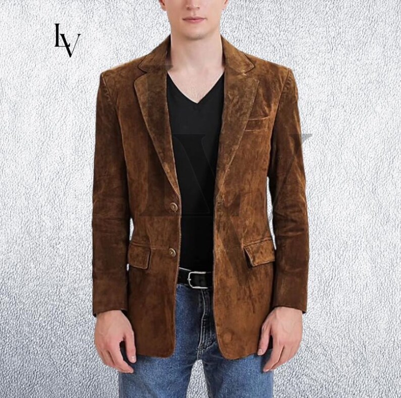 May include: A brown suede blazer with a two-button closure, notched lapels, and two front pockets. The blazer is worn over a black V-neck shirt and blue jeans. The image features the letters "lv" in the upper left corner.