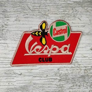 May include: Embroidered Vespa Club patch with a red background and white lettering. The patch features a stylized bee with yellow and black wings, and a green and white Castrol logo.