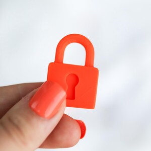 May include: A bright orange padlock with a keyhole cutout. The padlock is held against a white background. The padlock is a solid color and has a rounded handle.