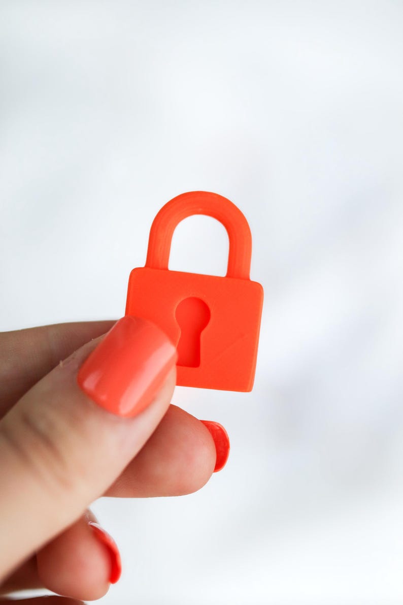 May include: A bright orange padlock with a keyhole cutout. The padlock is held against a white background. The padlock is a solid color and has a rounded handle.